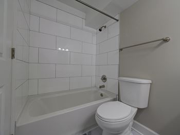 A white toilet sits next to a bathtub in a bathroom.